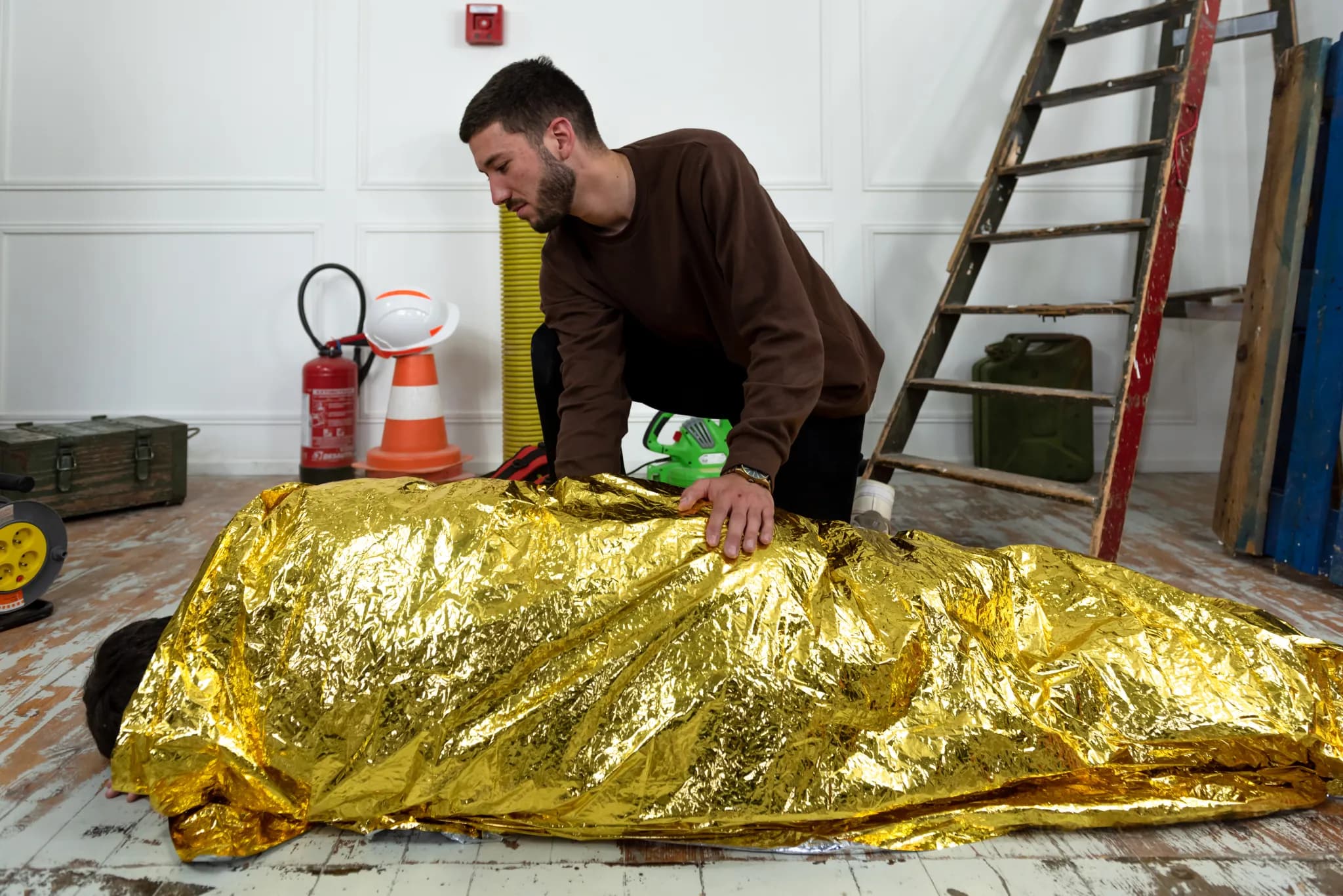 Homme-couverture-survie Homme utilisant une couverture de survie sur une personne allongée.